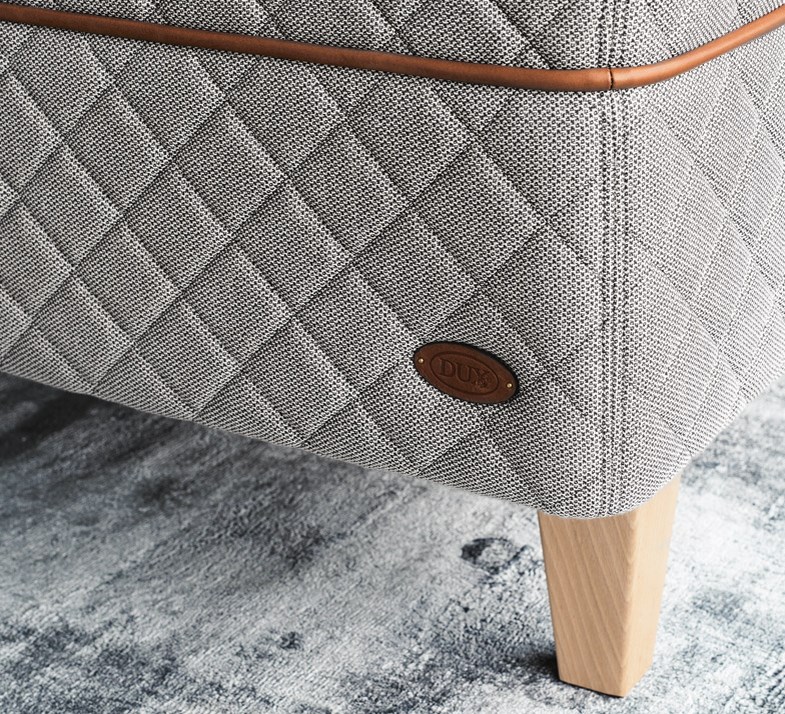 Detail of the DUX 3003 bed and tapered bed legs on a light green carpet. 